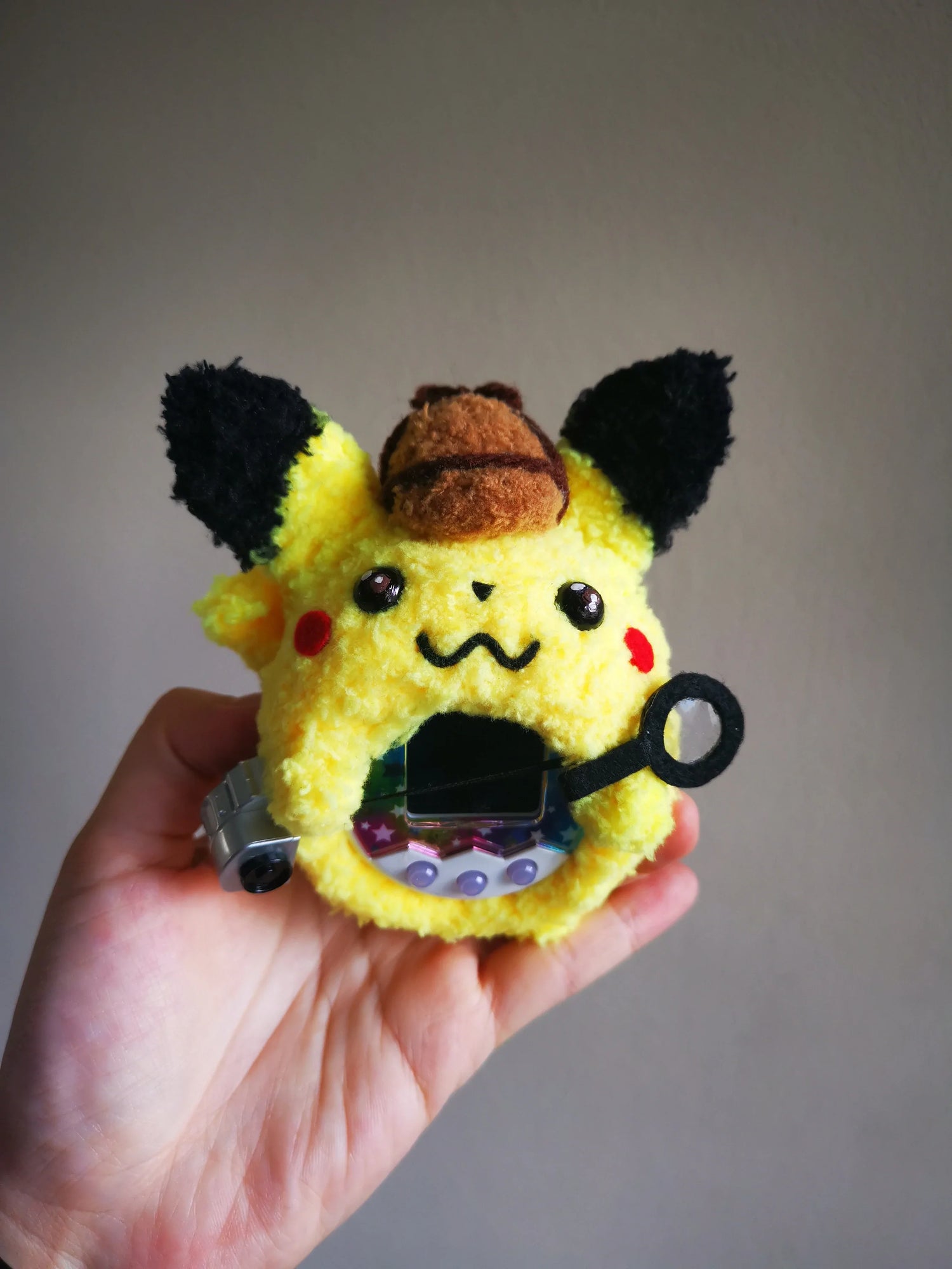 https://fuzzy-n-chic.com/cdn/shop/products/Detective-Pikachu-Fuzzy-Tamagotchi-Cover-Fuzzy-N-Chic-978_1500x.webp?v=1673664308